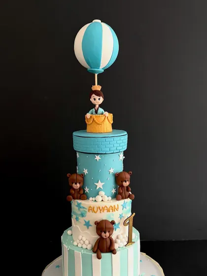 A close-up of the four-tiered first birthday cake, showing the adorable teddy bears and starry details.