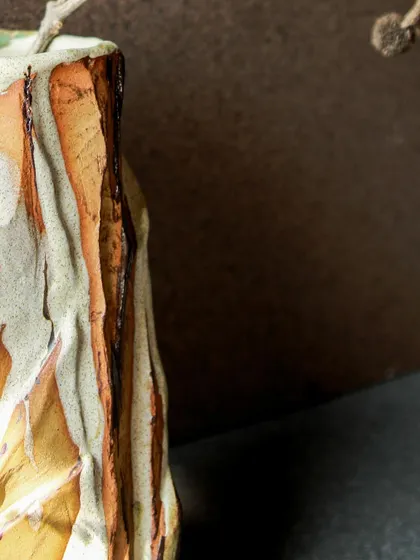 A close-up of a Kurinuki vase, showing the deep, chiseled textures that mimic a mountain facade. The process is sculptural, revealing the form as I carve away the clay.