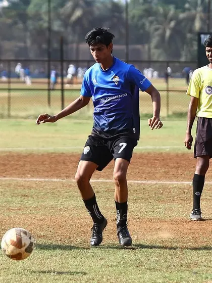 A player with the ball at his feet, looking for a pass while a referee looks on. Our league games are officiated professionally.