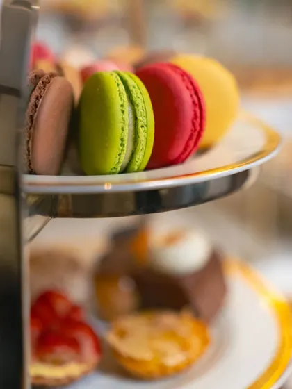A tiered stand showcasing a variety of French macarons and other petite desserts. This high-tea style presentation adds a touch of Parisian chic to any event.