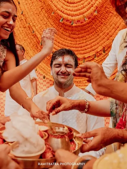 The groom smiles as family members perform rituals during a pre-wedding ceremony in Goa.