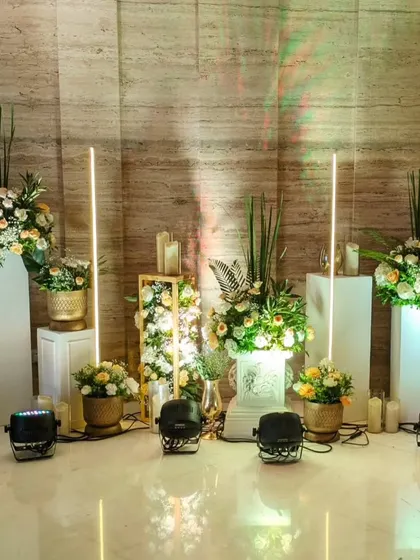 This modern decor corner features floral arrangements on illuminated pedestals, accented by tall, glowing light sticks for a chic and contemporary feel.