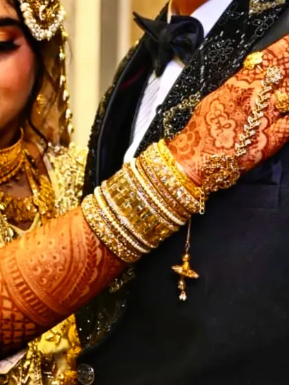 An artistic shot of a bride's hands, where the deep stain of the henna perfectly complements her golden wedding attire.
