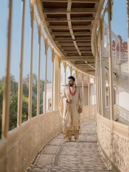 The groom walks along a beautiful arched bridge at a Jaipur palace, his traditional attire and the architectural details creating a timeless image.