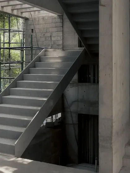 A steel and concrete staircase takes shape within the Courtyard House. The image shows the raw structure and the interplay between different materials before the finishing touches are applied.