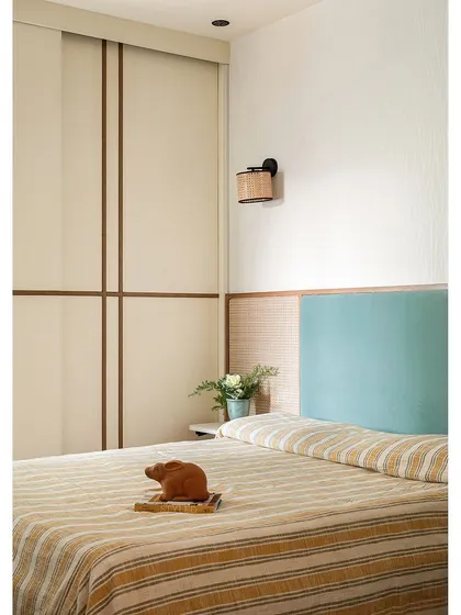 The master bedroom in 'The Boho Escape' uses a mint blue headboard and cane detailing to create a rustic yet fresh look. A fold-down ledge by the bed serves as a convenient nightstand.