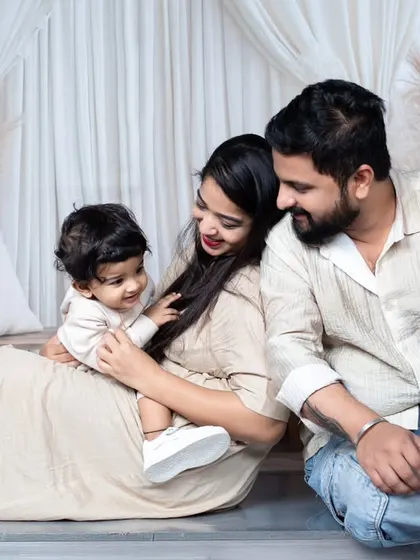 A relaxed and candid photo of a family of three sitting together on the floor, sharing a natural interaction.