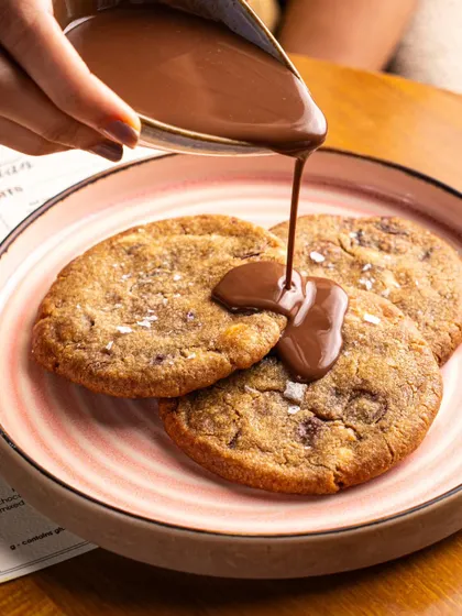 A controlled chocolate pour over freshly baked cookies for Bastian. This action shot is all about capturing the rich, flowing texture of the chocolate, adding a sense of indulgence and movement to the photograph.