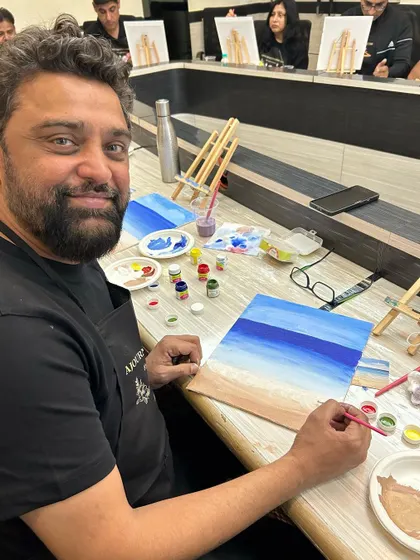 A smiling participant, happy with his progress on his beach painting.