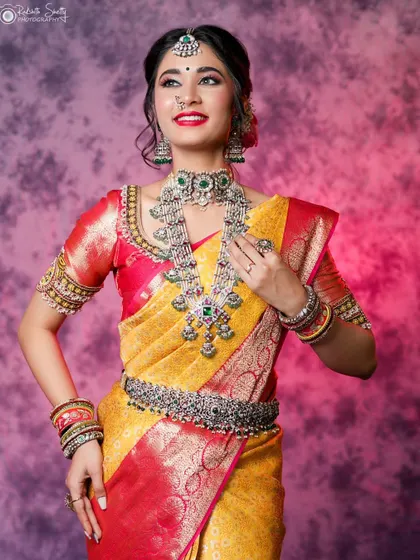 A full-length portrait of a model in a vibrant yellow and red saree. Her confident pose and the stunning silver jewelry create a powerful and elegant image.