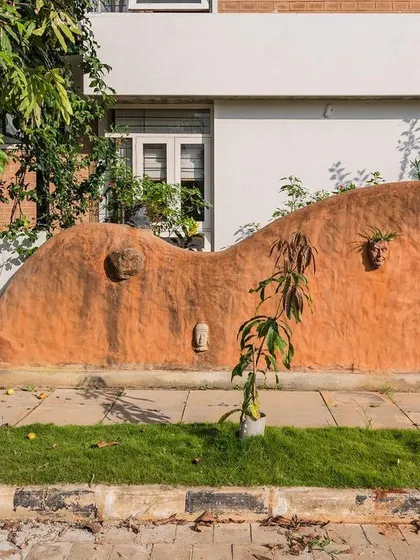 This sculptural compound wall is made from cob, a natural building mixture of soil, water, and fibrous material. It serves as a beautiful, organic introduction to the sustainable home that lies behind it.