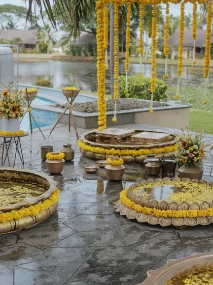 A serene poolside Haldi setup with traditional brass urlis and marigold decorations.