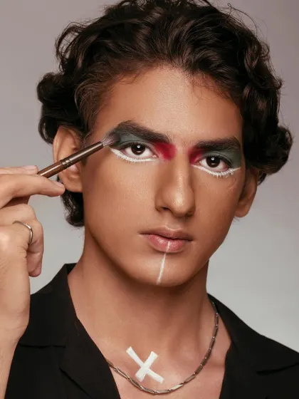 A direct and powerful portrait of a male model having eyeshadow applied. The shot is a celebration of gender-fluid beauty and artistic expression. It demonstrates the makeup brush's capability for detailed and graphic eye work.