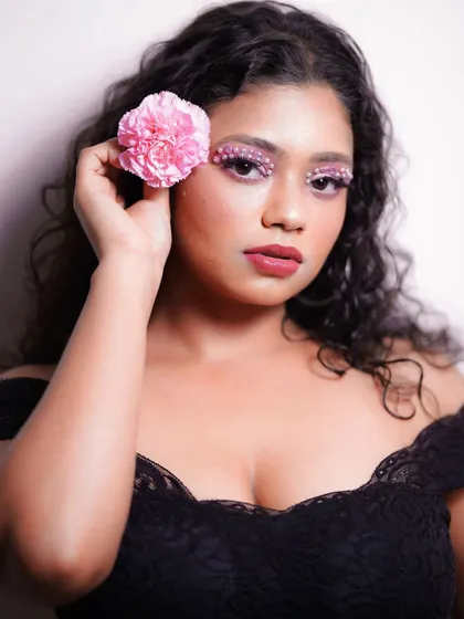 A portrait showcasing the full effect of the pearl eye makeup. The pink tones and floral prop create a soft, romantic, and imaginative theme for this beauty shoot.