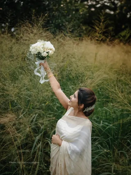 The bride joyfully raises her bouquet, celebrating their union during an outdoor photoshoot.