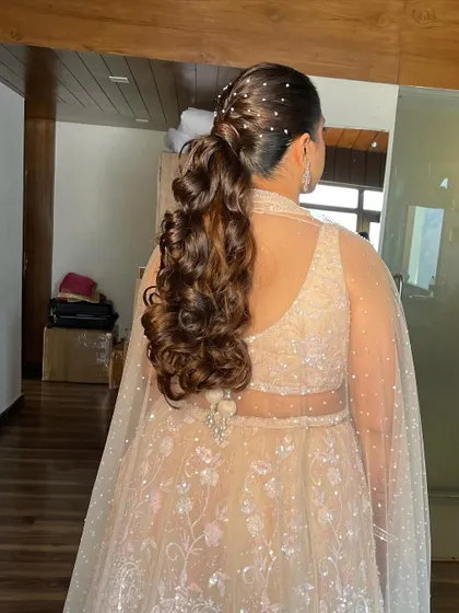 A messy ponytail with pearl accessories scattered throughout. This is a great style for a Sangeet or engagement party.