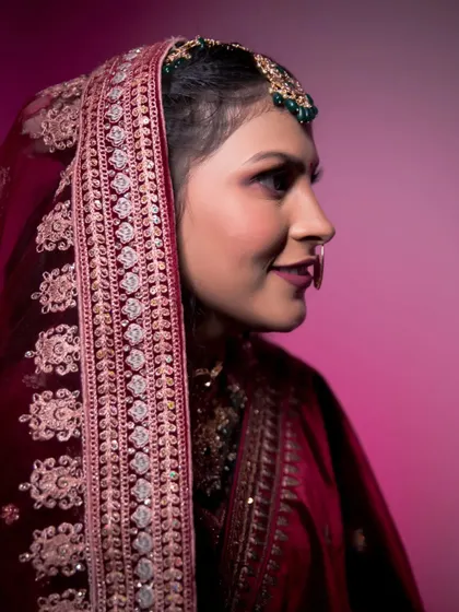 A beautiful profile shot of the bride, highlighting her intricate veil, makeup, and traditional nose ring.
