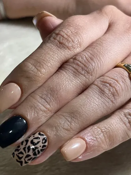 A classic and chic animal print design. This look pairs a neutral beige and solid black polish with a timeless leopard print accent nail.