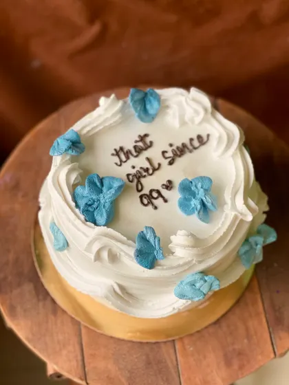 A side view of the "that girl since 99" cake, showing the fluffy buttercream swirls.