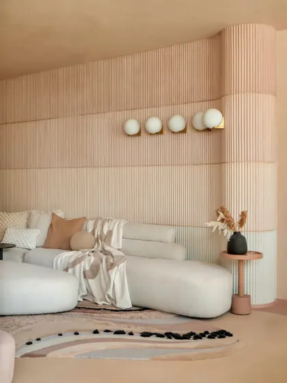 The organic shapes of the furniture and the custom-designed rug echo the fluid lines of the ceiling. Every element in this living room is designed to feel soft, connected, and harmonious.