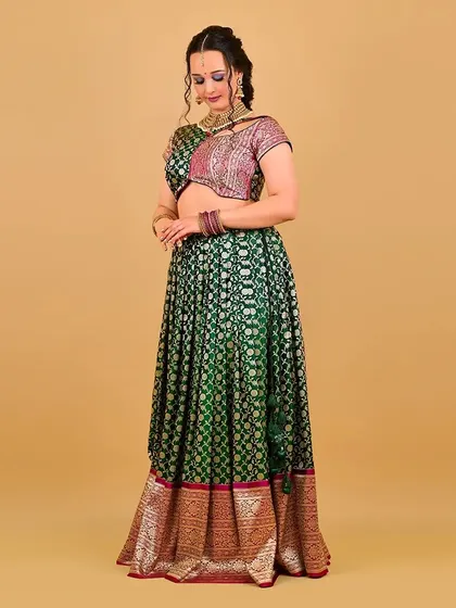 A full-length shot with a graceful pose. The makeup helps tie the entire look together, from the rich green of the lehenga to the shimmering jewellery.