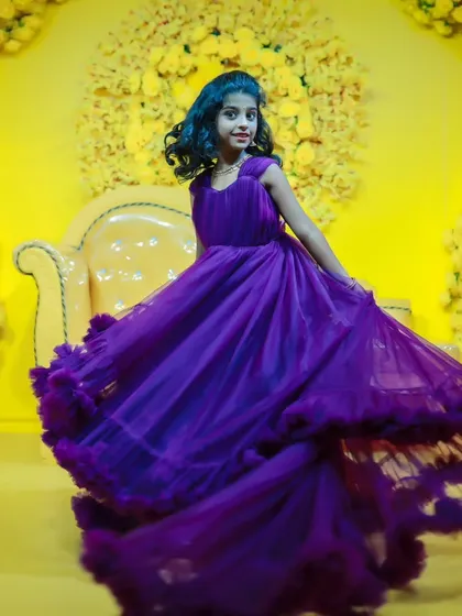 A dynamic shot of a young girl twirling in a purple ruffled gown, showcasing the beautiful movement of the dress.