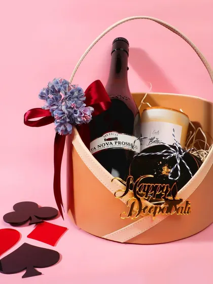 A Diwali-themed gift basket with a bottle of wine and a candle, styled with playing card motifs for a festive touch.