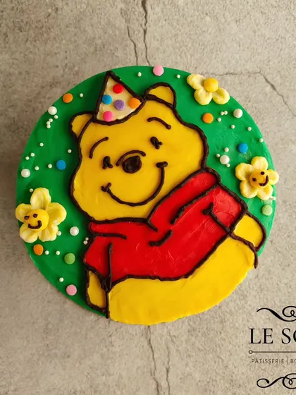 A cheerful Winnie the Pooh cake made with pure buttercream art. This half-kg Chunky Monkey cake features a happy Pooh bear in a party hat, ready to celebrate.