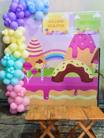 A combined balloon sculptor and tattoo station with a sweet Candyland theme, perfect for younger children.