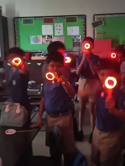 Students in a classroom hold up their glowing creations, a fun and visual way to learn about basic electronics and circuits.