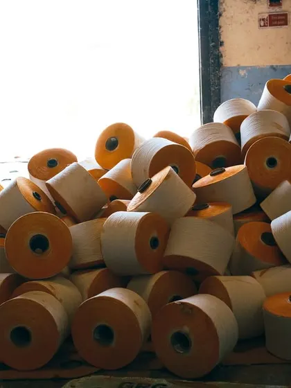 A behind-the-scenes look at the textile creation process. This image captures the abundance and raw texture of the yarn cones before they are woven into fabric, telling the story of beginnings.