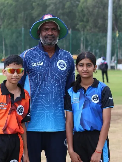 A coach stands proudly with two of his players, a boy and a girl, showcasing the inclusive nature of our academy.