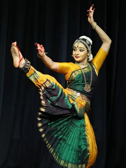 A high-kick pose demonstrating flexibility and control, performed during the Ninada Nruthyotsava.