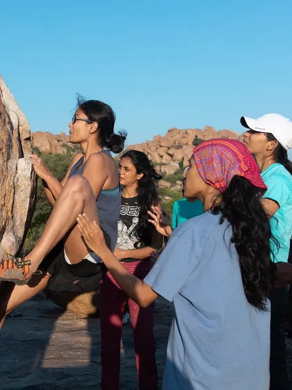 A climber fully focused on her handhold, with spotters ready. This image highlights the concentration and trust that are central to the climbing experience we foster.