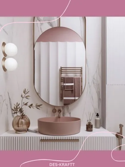 A close-up of the blush pink vessel sink and ribbed vanity, set against a dramatic marble wall. The oval mirror and globe sconces add a soft, modern touch.