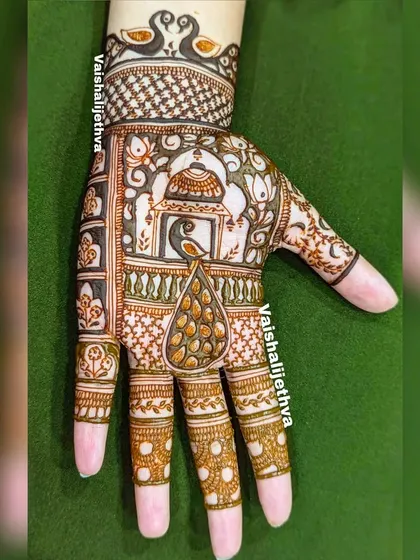 An Indian mehndi design with a peacock start-up. The main peacock motif is placed in a jharokha, creating a royal and traditional look.