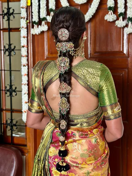 A stunning view of a traditional bridal braid, adorned with multiple gold jada billalu and a floral arrangement at the top. This hairstyle is a work of art.