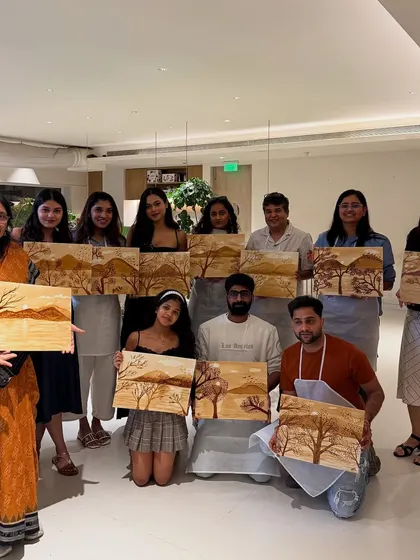 A group of happy painters showing off their coffee paintings. It's amazing to see the range of sepia tones and landscapes created using just coffee.