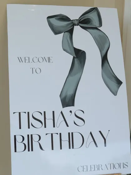 A chic welcome sign for "Tisha's Birthday," featuring a stylish bow graphic and elegant typography that sets the tone for a sophisticated celebration.