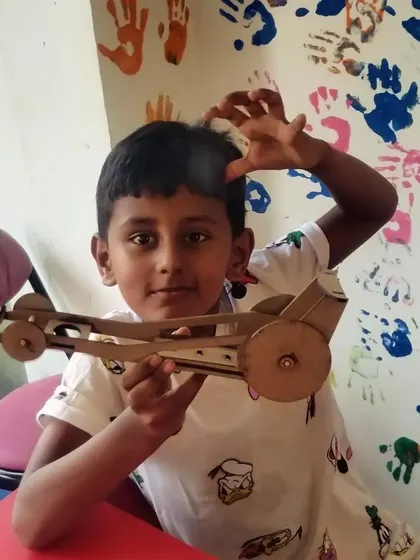 A fun pose with a finished project! This student is excited about the wooden car he built himself.