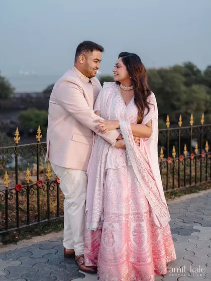A full-length shot of the couple, showcasing the bride's beautiful pink lehenga.