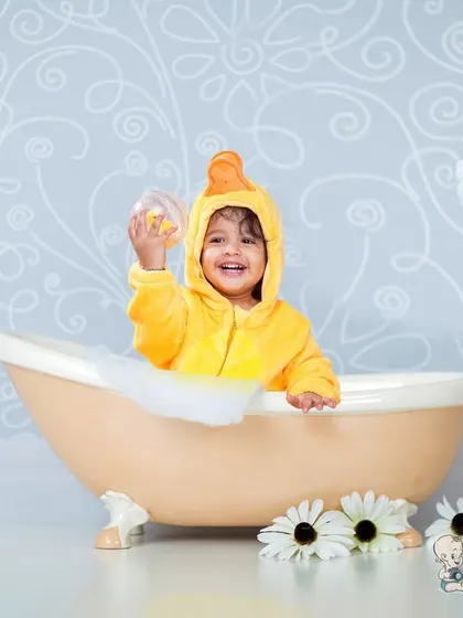 A toddler having a blast in a ducky-themed bubble bath shoot. Dressed in a duck costume and sitting in a vintage tub, his joyful expression is absolutely infectious.