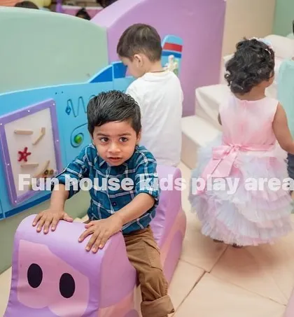 A close-up of a child enjoying the soft rocker and the interactive activity wall in our pastel play area.