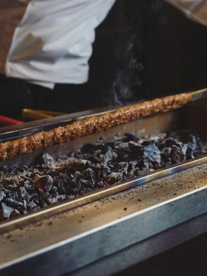 A close-up of our Adana kebab being cooked over hot coals. This traditional method ensures a smoky flavor and perfectly cooked meat, just as you would find in Turkey.