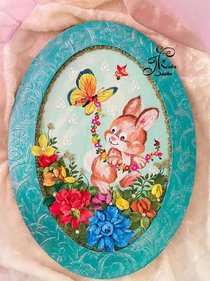 The full view of the "Bunny in the Spring" oval panel. The textured blue frame complements the colors in the artwork perfectly.