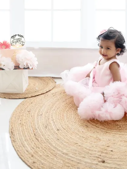 A happy smile from the birthday girl as she sits next to her cake. The simple, elegant setup is perfect for timeless portraits.