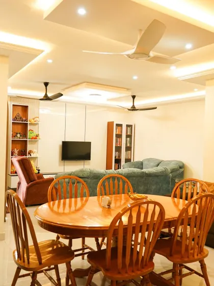 A view of the spacious living and dining area, unified by a clean design aesthetic. The wooden dining set provides a warm contrast to the cool tones of the sofas.