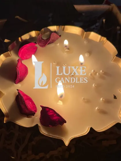 A lit lotus urli candle, adorned with rose petals and pearls, creating a beautiful, warm glow.