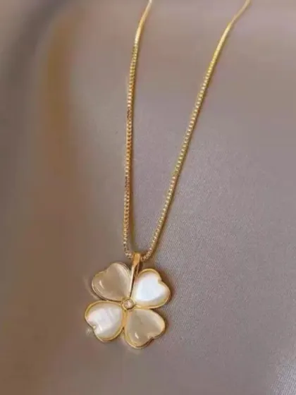 This charming necklace features a four-leaf clover pendant made of white mother-of-pearl on a delicate gold-toned chain. It's a symbol of luck and a beautiful accessory.