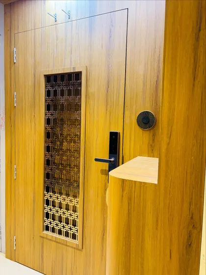 This safety door combines a warm wood laminate with a geometric metal jaali. The smart lock adds a layer of modern security.